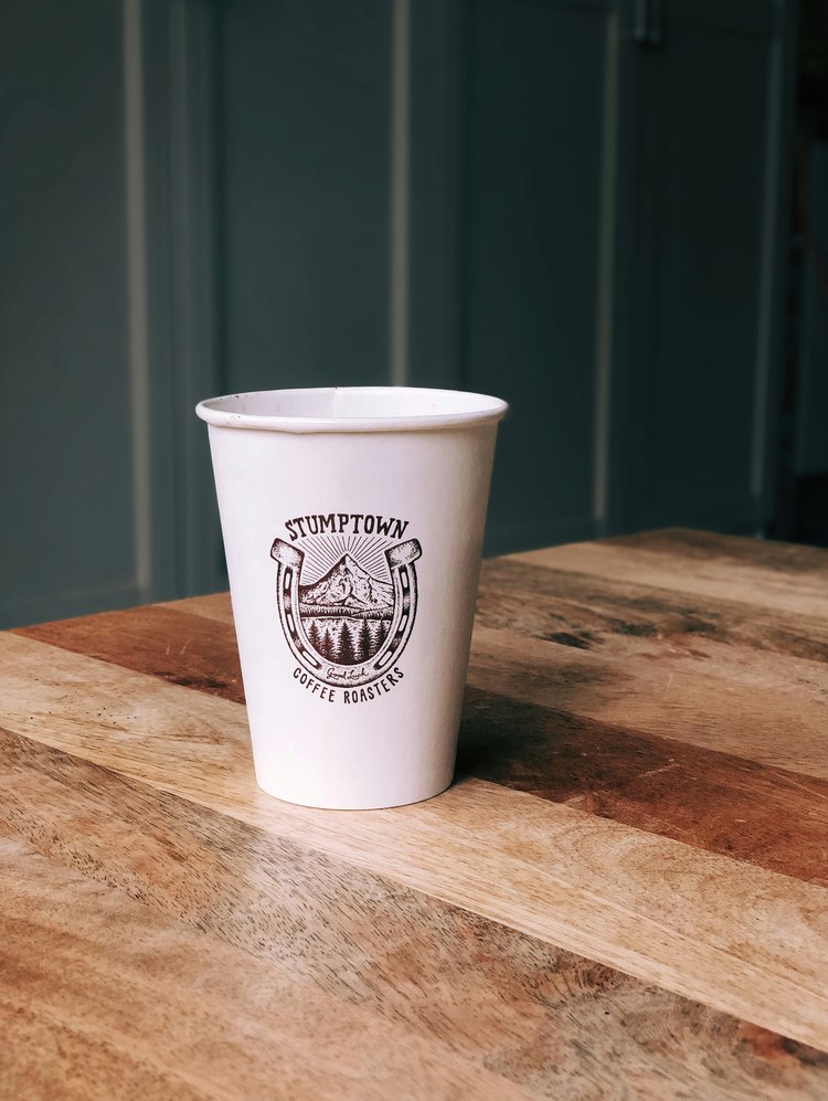 eine weiße Tasse, die auf einem Holztisch sitzt